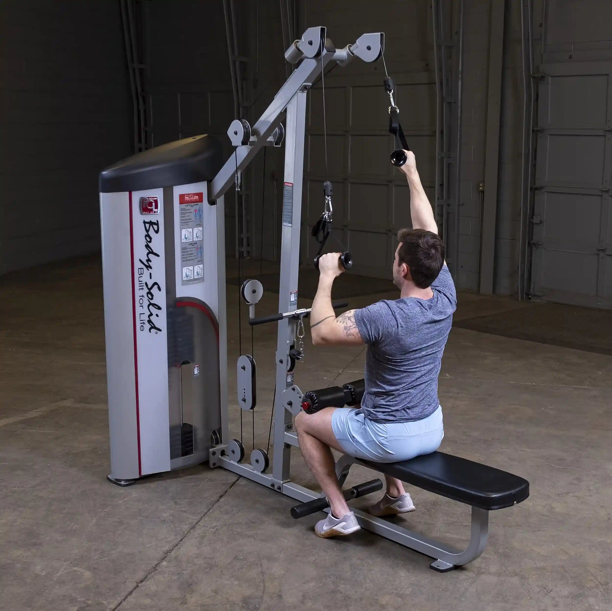 A person using the Body-Solid Pro ClubLine Series 2 Lat Pulldown & Seated Row Machine S2LAT in a gym setting, performing a lat pulldown exercise.