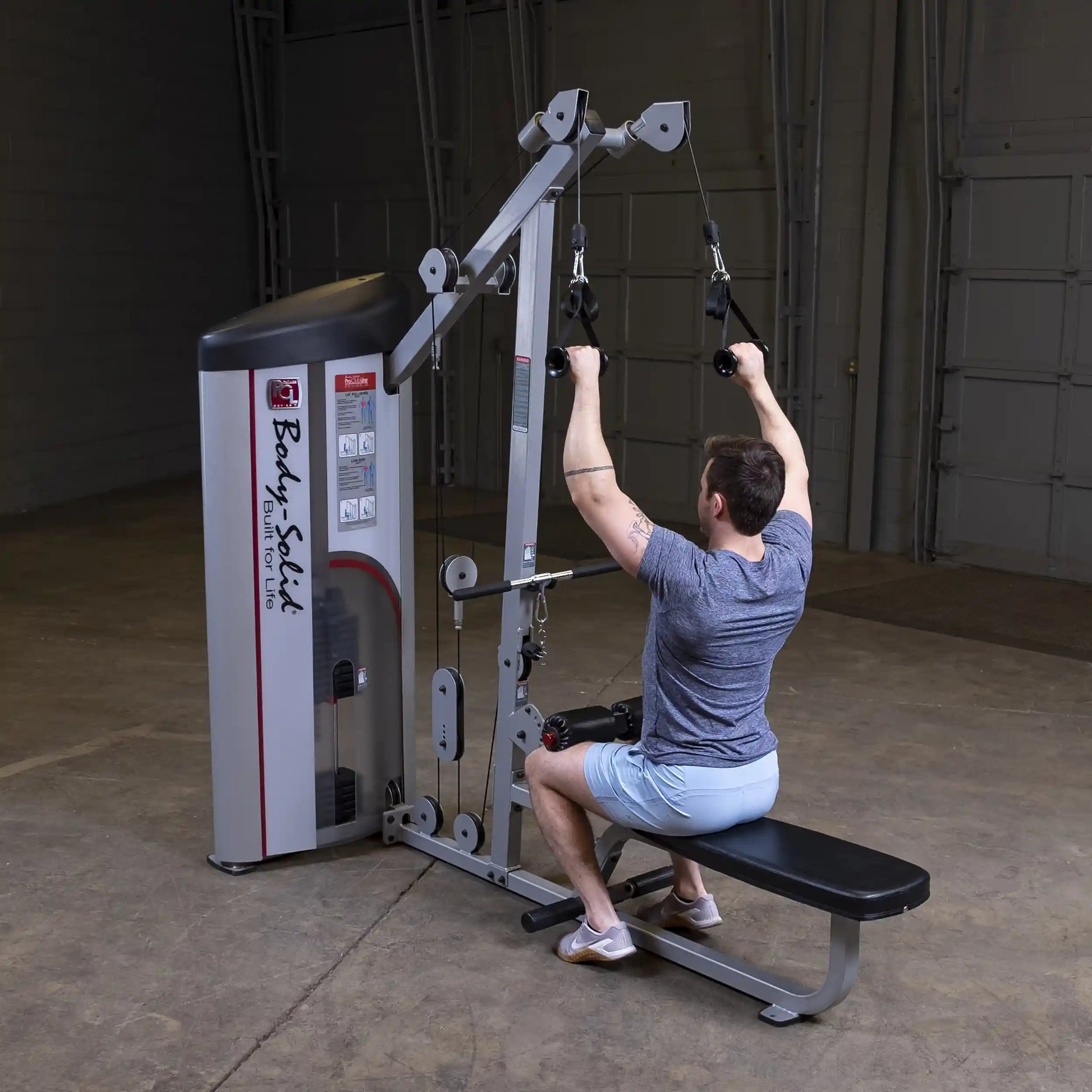 A person using the Body-Solid Pro ClubLine Series 2 Lat Pulldown & Seated Row Machine S2LAT in a gym setting, performing a lat pulldown exercise.
