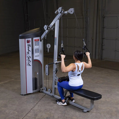 A person using the Body-Solid Pro ClubLine Series 2 Lat Pulldown & Seated Row Machine S2LAT in a gym setting, performing a lat pulldown exercise.