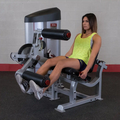 A person using the Body-Solid Pro ClubLine Series 2 Leg Extension & Leg Curl Machine S2LEC in a gym setting, performing leg extensions with a focused expression.