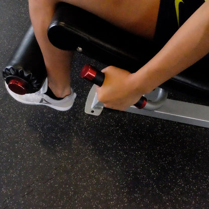 Close-up of a person's hand gripping the handle of the Body-Solid Pro ClubLine Series 2 Leg Extension & Leg Curl Machine S2LEC, with a focus on the leg support and foot positioning.