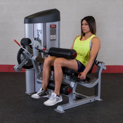 A woman using the Body-Solid Pro ClubLine Series 2 Leg Extension & Leg Curl Machine S2LEC in a gym setting, demonstrating leg extension exercise.