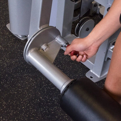 Close-up of a hand adjusting the Body-Solid Pro ClubLine Series 2 Leg Extension & Leg Curl Machine S2LEC, showcasing the machine's adjustable components.