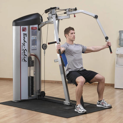 A person using the Body-Solid Pro ClubLine Series 2 Pec Fly & Rear Delt Machine S2PEC for strength training, seated with arms extended in front, in a gym setting.