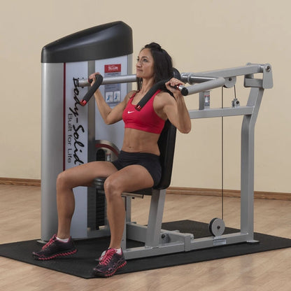 A woman using the Body-Solid Pro ClubLine Series 2 Shoulder Press Machine S2SP in a gym setting, demonstrating proper form while performing a shoulder press exercise.