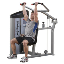 A man using the Body-Solid Pro ClubLine Series 2 Shoulder Press Machine S2SP, performing an overhead press while seated, in a gym setting.