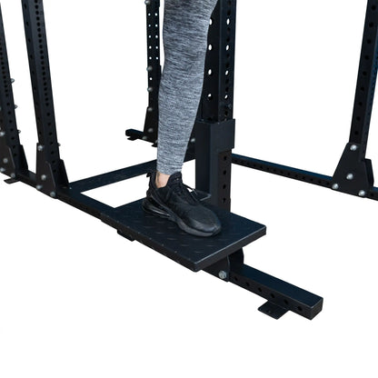 Close-up of a foot on the Body-Solid Pro ClubLine Spotter Platforms SPRSP, positioned on a weightlifting rack.