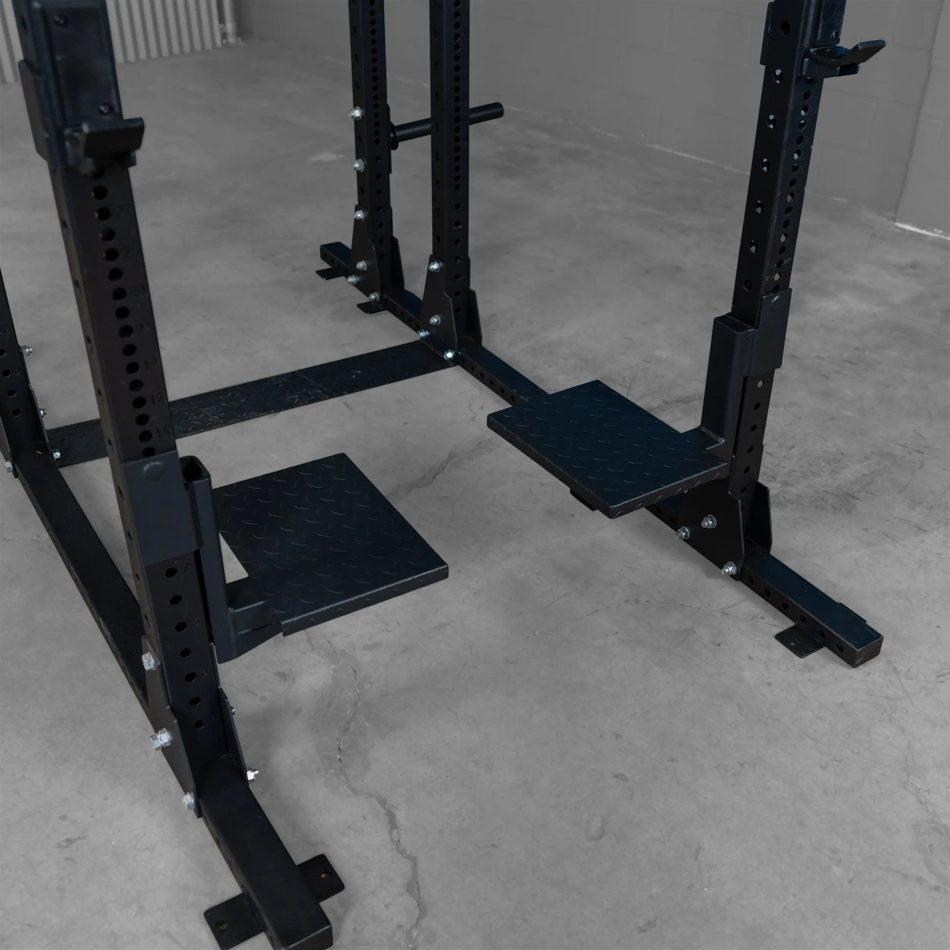 Close-up view of Body-Solid Pro ClubLine Spotter Platforms SPRSP, featuring textured black platforms on a sturdy weightlifting rack.