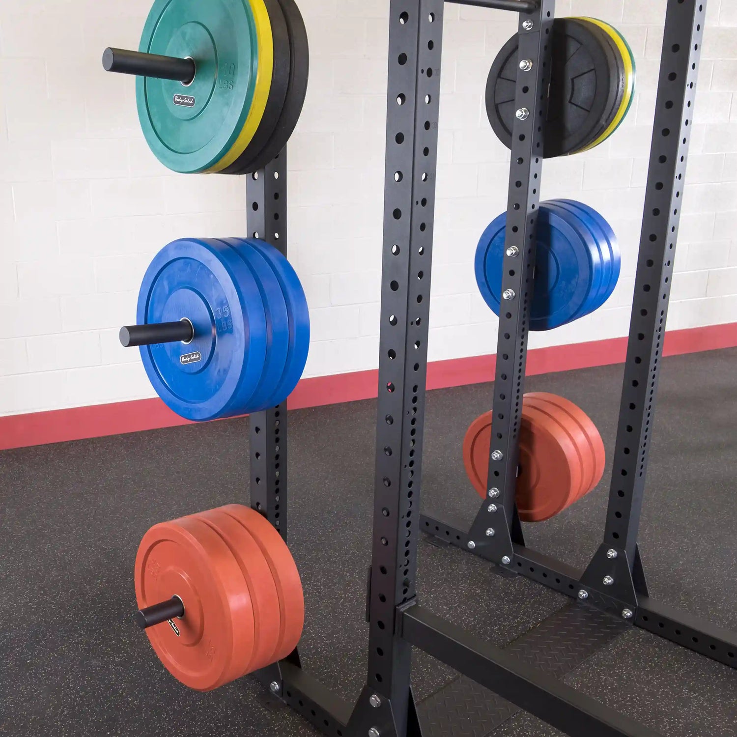 Image of a Body-Solid Pro ClubLine Weight Plate Horns Attachment SPRWPH with various colored weight plates organized on a vertical rack in a gym setting.