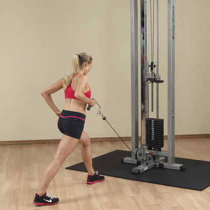 A woman performing a cable exercise using the Body-Solid Pro Clubline Cable Crossover SCC1200G, showcasing proper form in a gym setting.