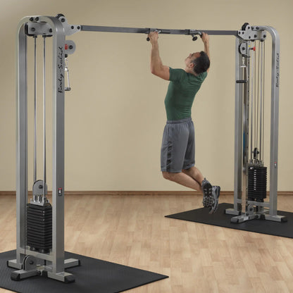 A man performing a pull-up on the Body-Solid Pro Clubline Cable Crossover SCC1200G, showcasing the exercise equipment in a gym setting.