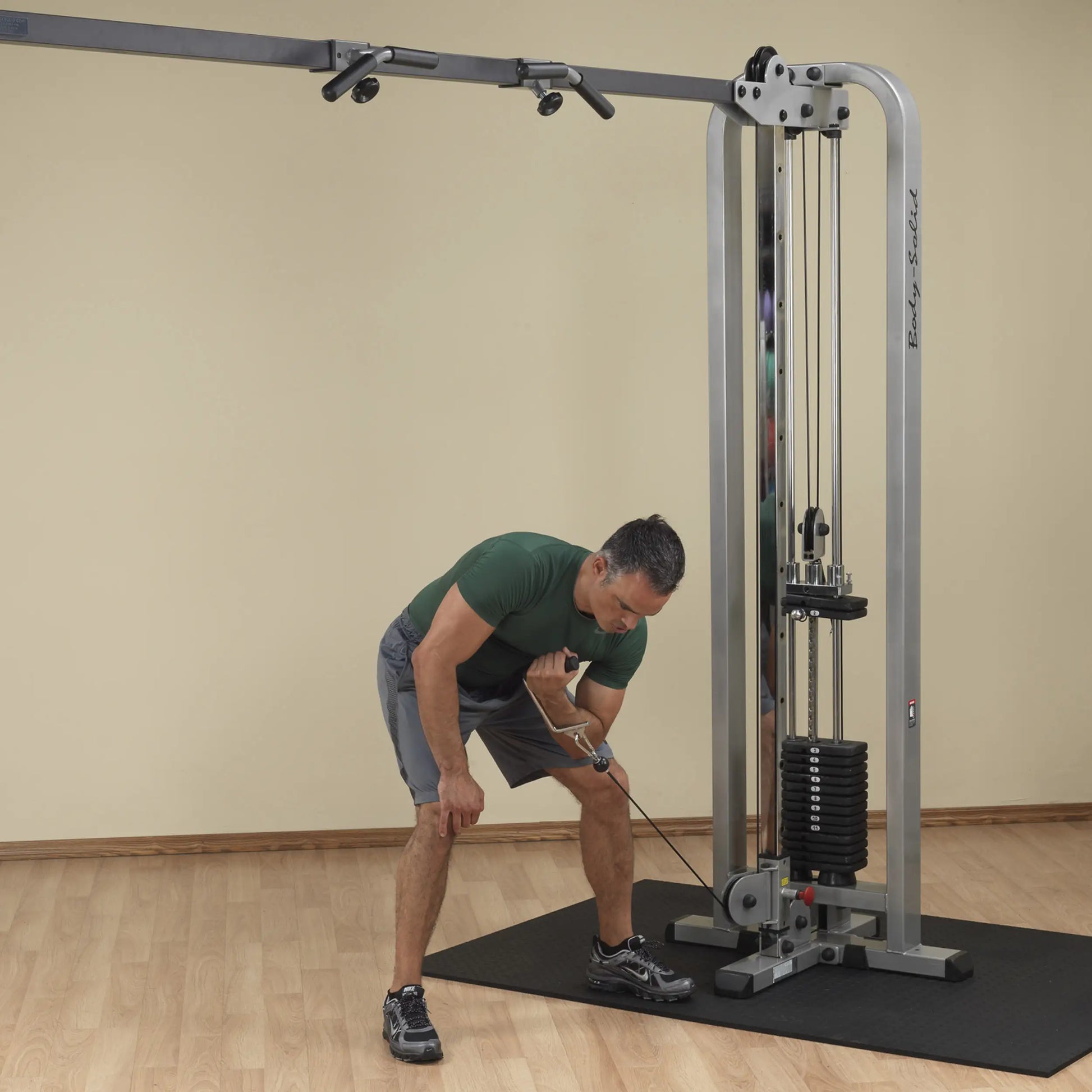 A man performing an exercise using the Body-Solid Pro Clubline Cable Crossover SCC1200G, demonstrating proper form while pulling the cable towards him in a gym setting.