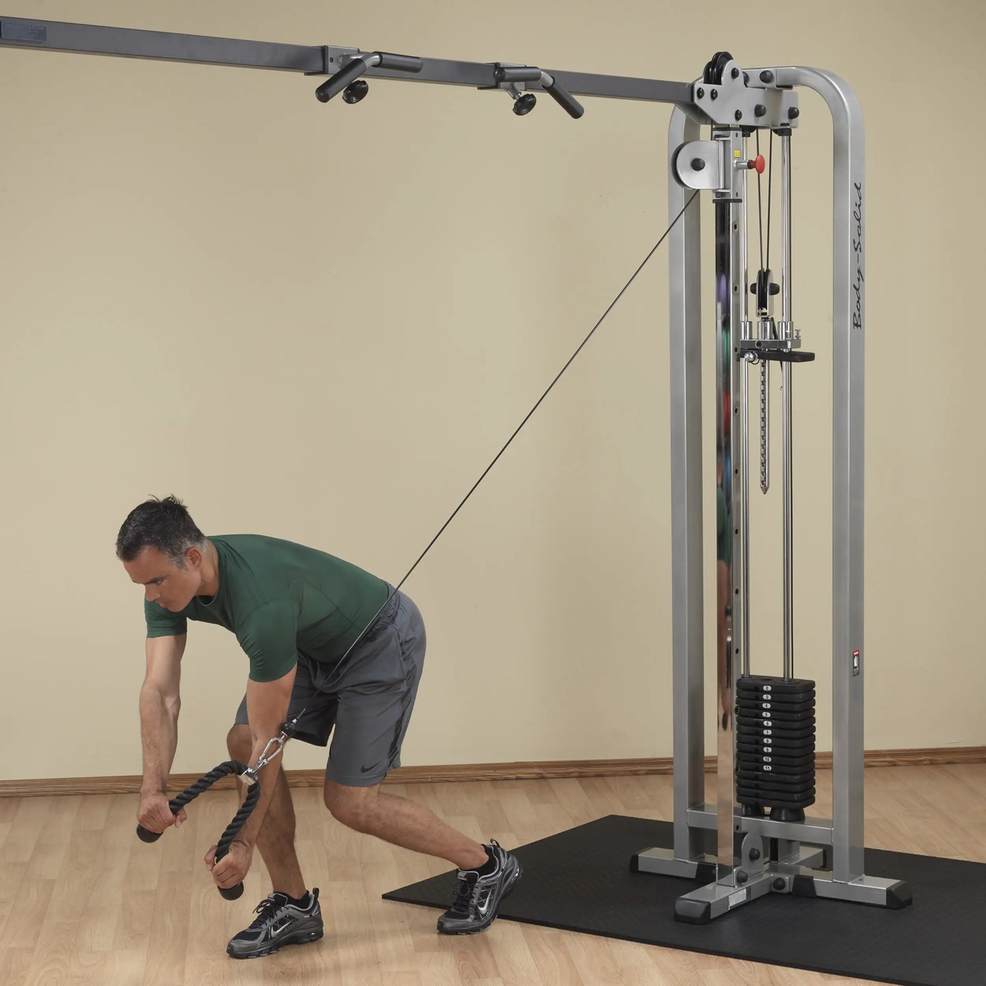 A man performing an exercise on the Body-Solid Pro Clubline Cable Crossover SCC1200G, demonstrating proper form as he pulls the cable with both hands.