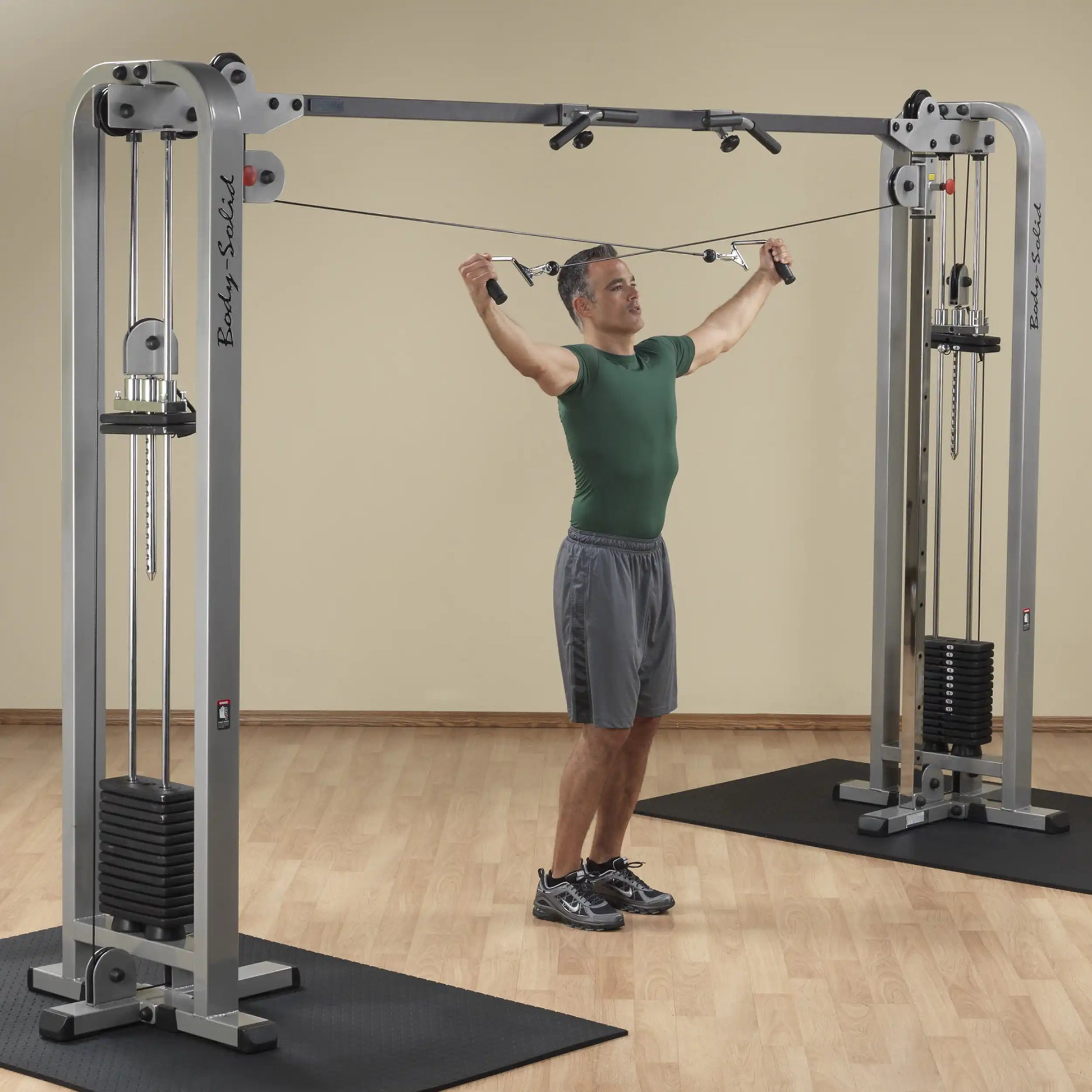 A man performing a cable crossover exercise using the Body-Solid Pro Clubline Cable Crossover SCC1200G in a gym setting.