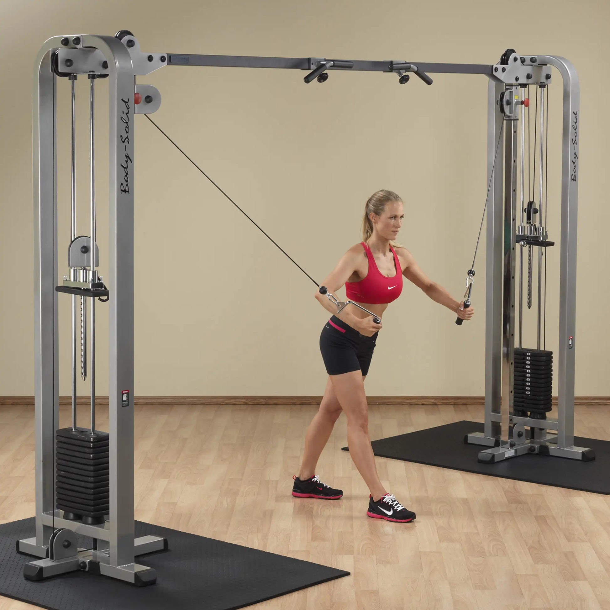Woman using the Body-Solid Pro Clubline Cable Crossover SCC1200G for strength training in a gym setting.
