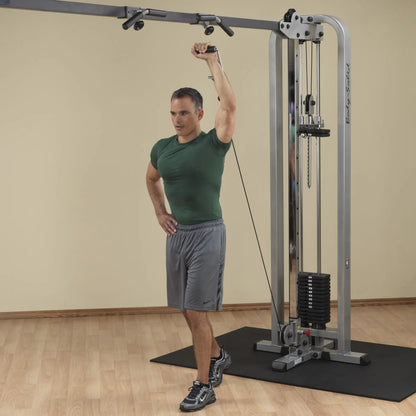 A man demonstrating an exercise using the Body-Solid Pro Clubline Cable Crossover SCC1200G, with one arm raised holding a cable attachment.