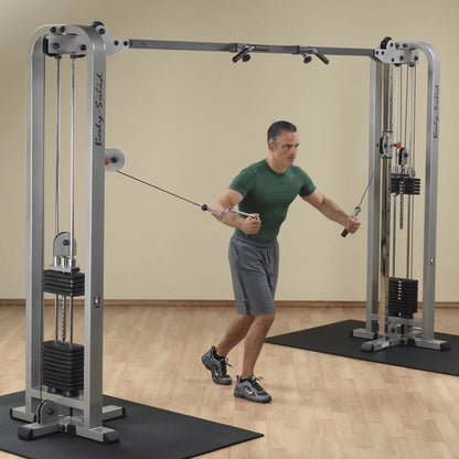 A man performing an exercise using the Body-Solid Pro Clubline Cable Crossover SCC1200G in a fitness studio, showcasing the cable machine and weights.