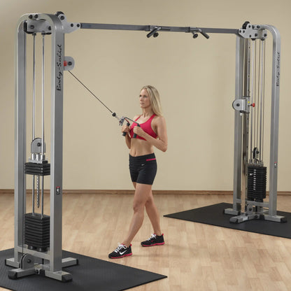 A woman performing an exercise using the Body-Solid Pro Clubline Cable Crossover SCC1200G in a gym setting.