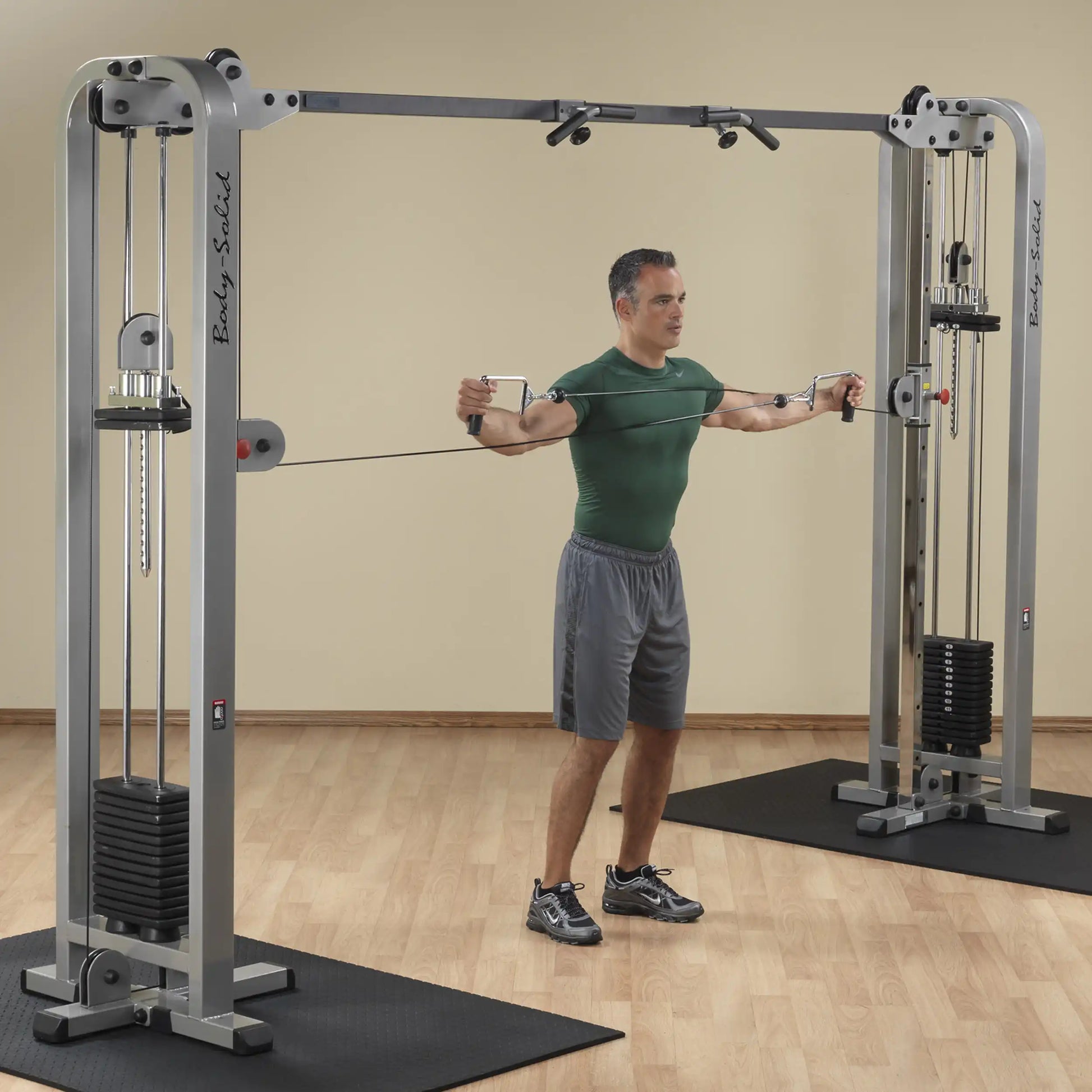 A man performing an exercise using the Body-Solid Pro Clubline Cable Crossover SCC1200G, showcasing the equipment's dual pulley system in a gym setting.