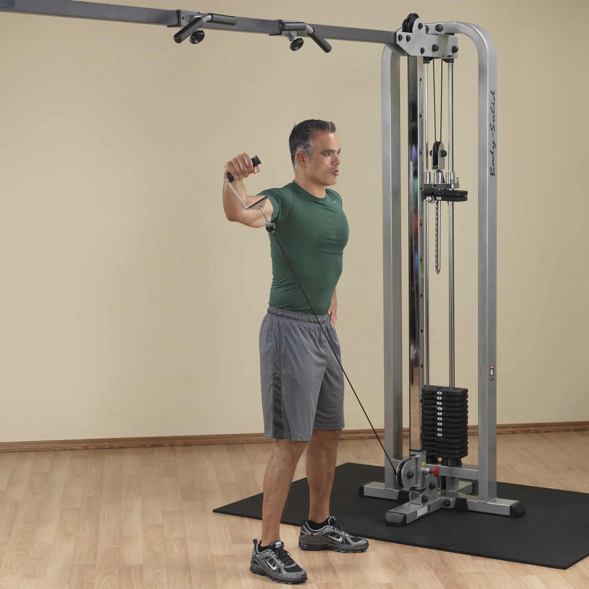 A man performing a cable exercise using the Body-Solid Pro Clubline Cable Crossover SCC1200G, demonstrating proper form while holding the cable handle with one arm.
