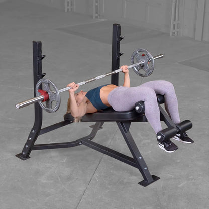 A person performing a decline bench press on the Body-Solid Pro Clubline Decline Olympic Bench SODB250, with a barbell and weight plates.