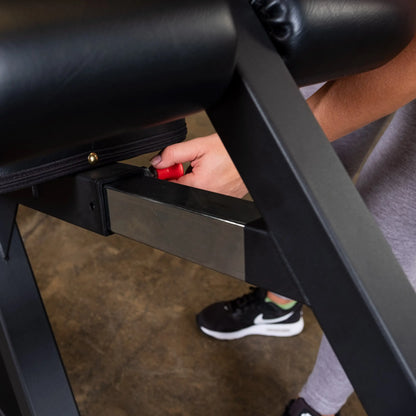 Close-up of a hand adjusting the Body-Solid Pro Clubline Decline Olympic Bench SODB250, showcasing the bench's adjustment mechanism.