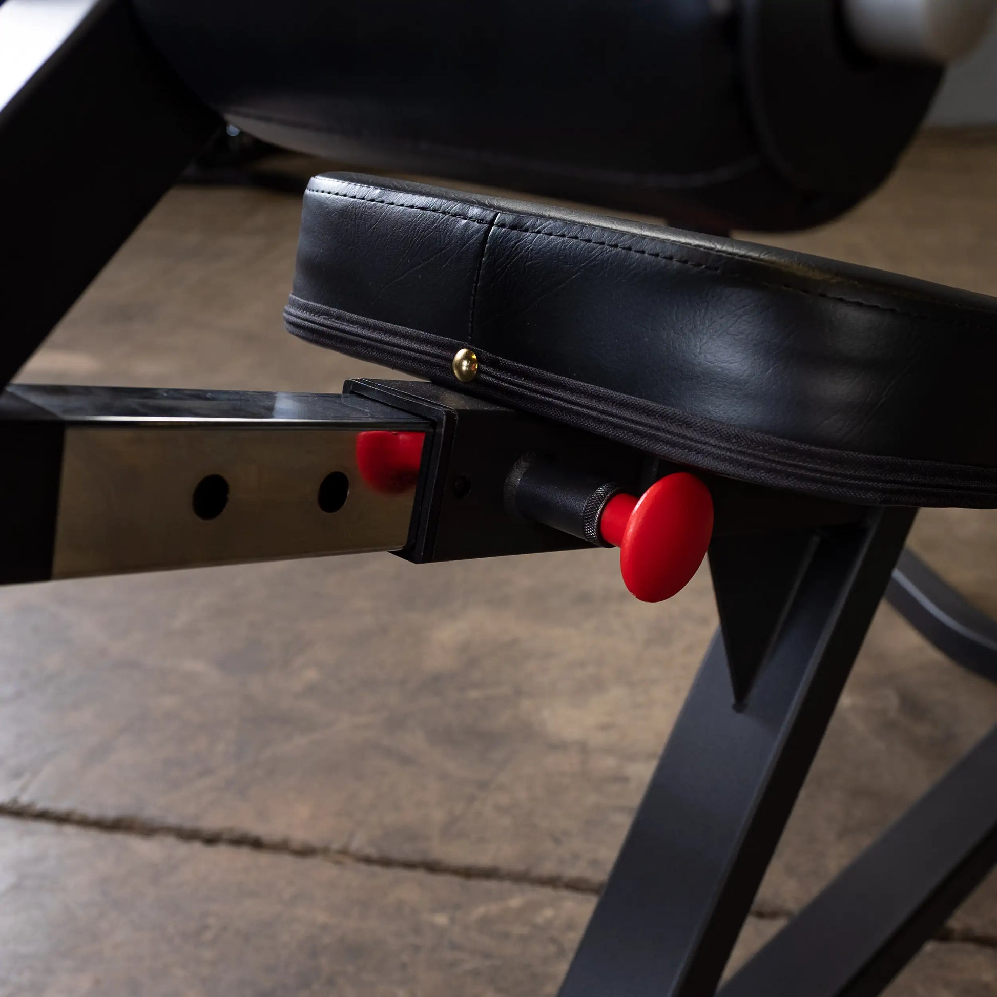Close-up view of the adjustment mechanism on the Body-Solid Pro Clubline Decline Olympic Bench SODB250, featuring a black padded seat and a red adjustment knob.