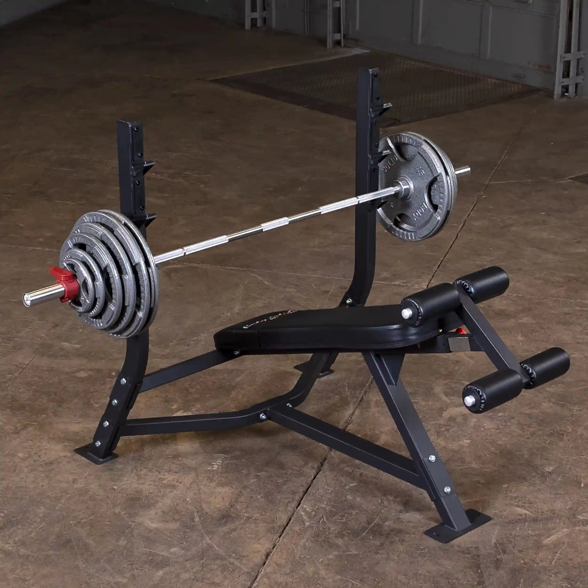 Body-Solid Pro Clubline Decline Olympic Bench SODB250 with a barbell and weight plates, positioned on a gym floor.