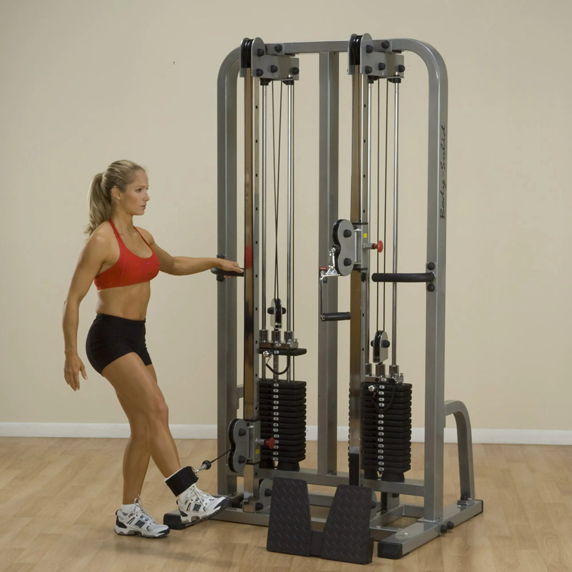 A woman using the Body-Solid Pro Clubline Dual Cable Column SDC2000G2 in a fitness studio, performing an exercise with a cable attachment.