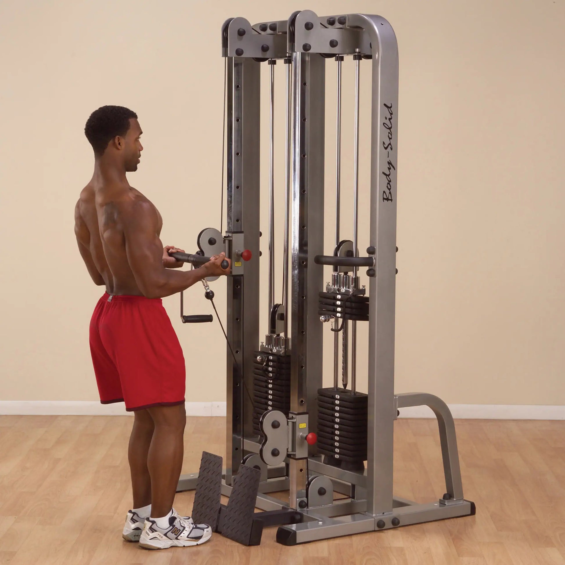 A person using the Body-Solid Pro Clubline Dual Cable Column SDC2000G2, performing an exercise with the cable machine in a gym setting.