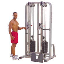 A fit man standing next to the Body-Solid Pro Clubline Dual Cable Column SDC2000G2, demonstrating its use in a gym setting.