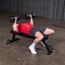 A person lying on a Body-Solid Pro Clubline Flat Bench SFB125, performing a dumbbell press exercise with weights in each hand.