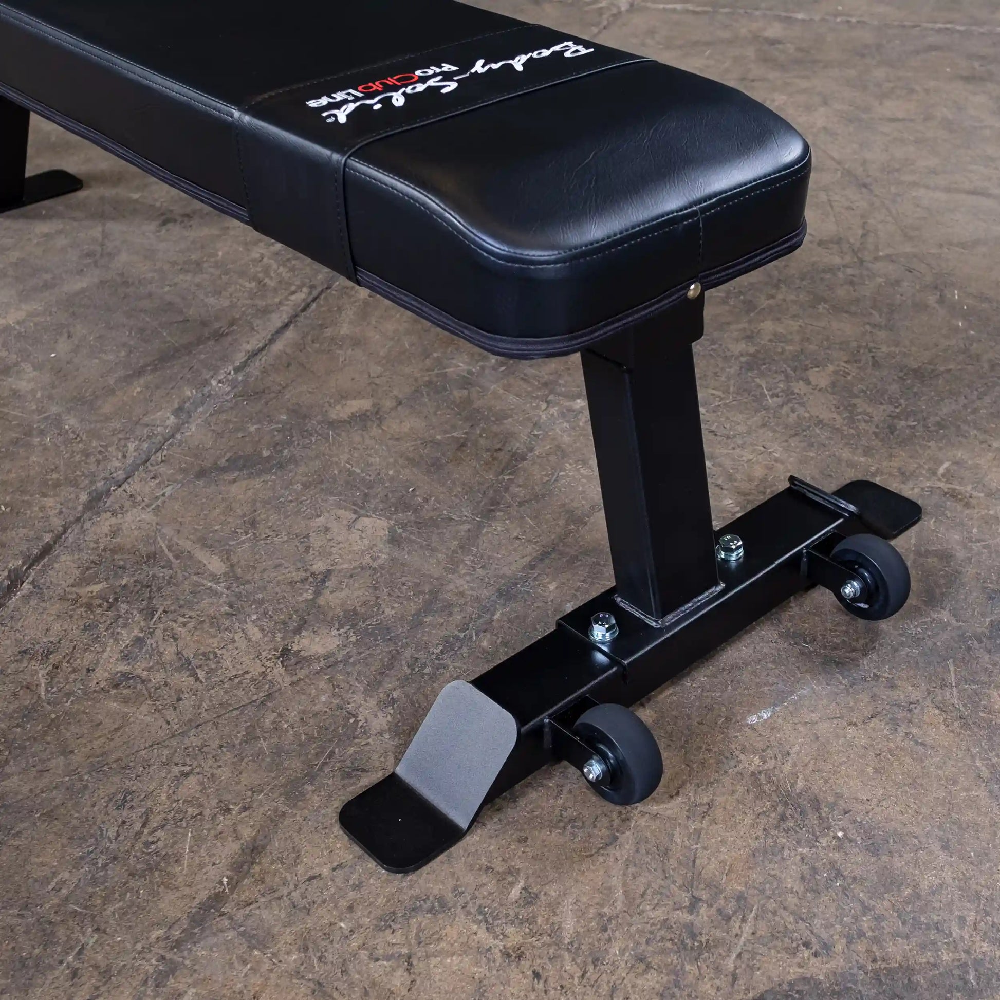 Close-up of the Body-Solid Pro Clubline Flat Bench SFB125, showcasing its padded black surface and sturdy base with wheels for easy mobility.