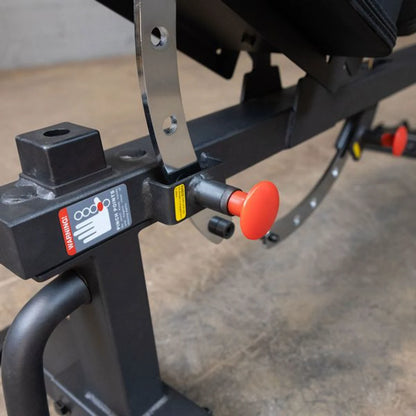 Close-up view of the adjustment mechanism and safety features on the Body-Solid Pro Clubline Flat/Incline Bench SFI20, highlighting the red release button and warning labels.