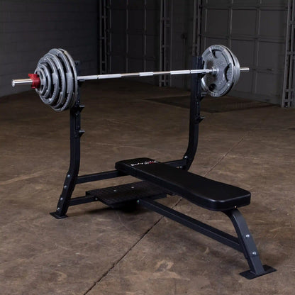 Body-Solid Pro Clubline Flat Olympic Bench SOFB250 with a barbell and weight plates, set on a gym floor.