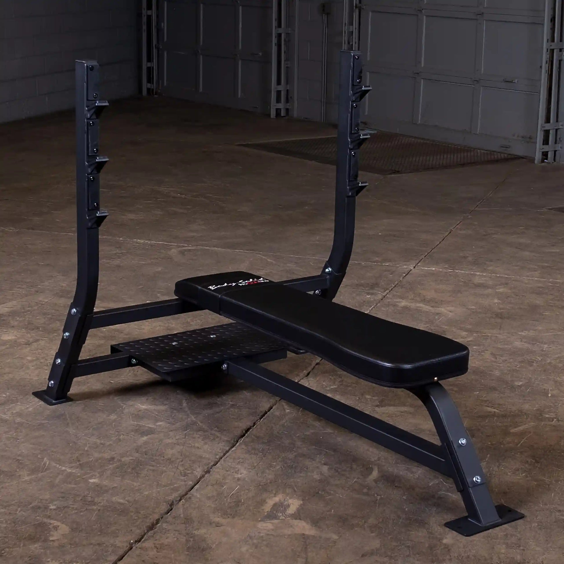Body-Solid Pro Clubline Flat Olympic Bench SOFB250 positioned in a gym setting with a concrete floor and garage-style background.