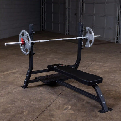 Body-Solid Pro Clubline Flat Olympic Bench SOFB250 with a barbell and weight plates, set up in a gym space with a concrete floor.