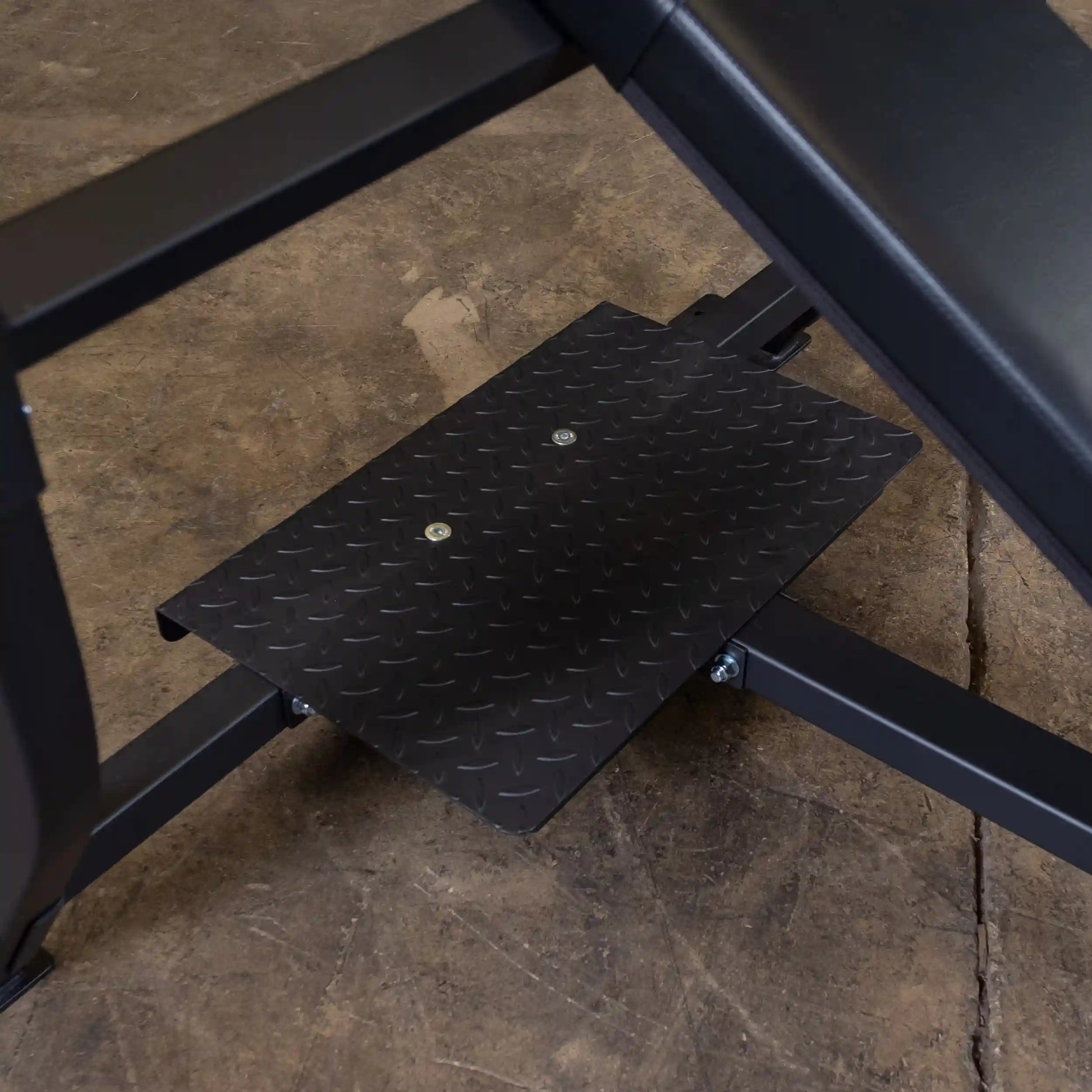 Close-up view of the Body-Solid Pro Clubline Incline Olympic Bench SOIB250, highlighting the sturdy diamond-plate foot support and metal frame on a concrete floor.