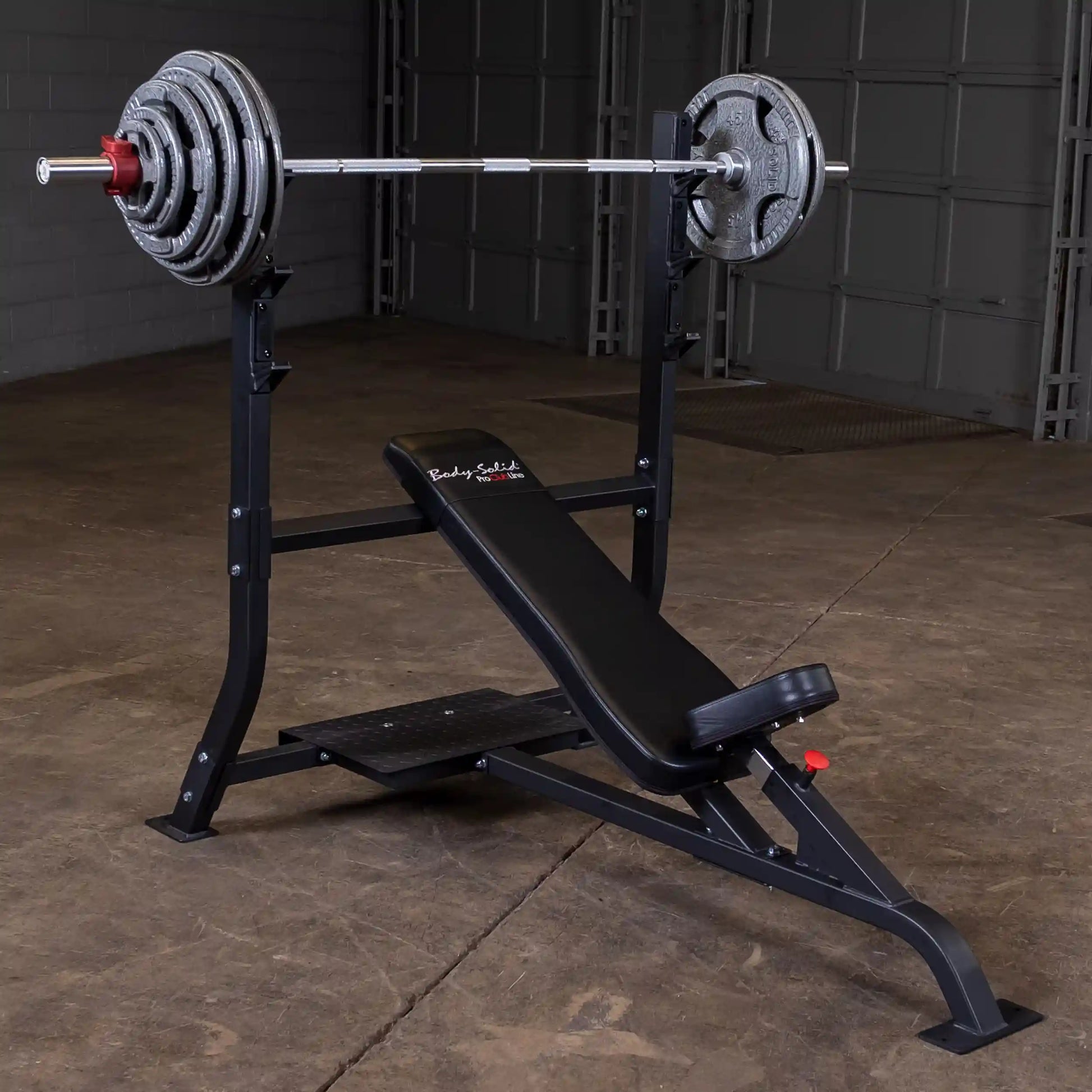 Body-Solid Pro Clubline Incline Olympic Bench SOIB250 featuring a black padded bench with a barbell and weights positioned on a sturdy frame in a gym setting.