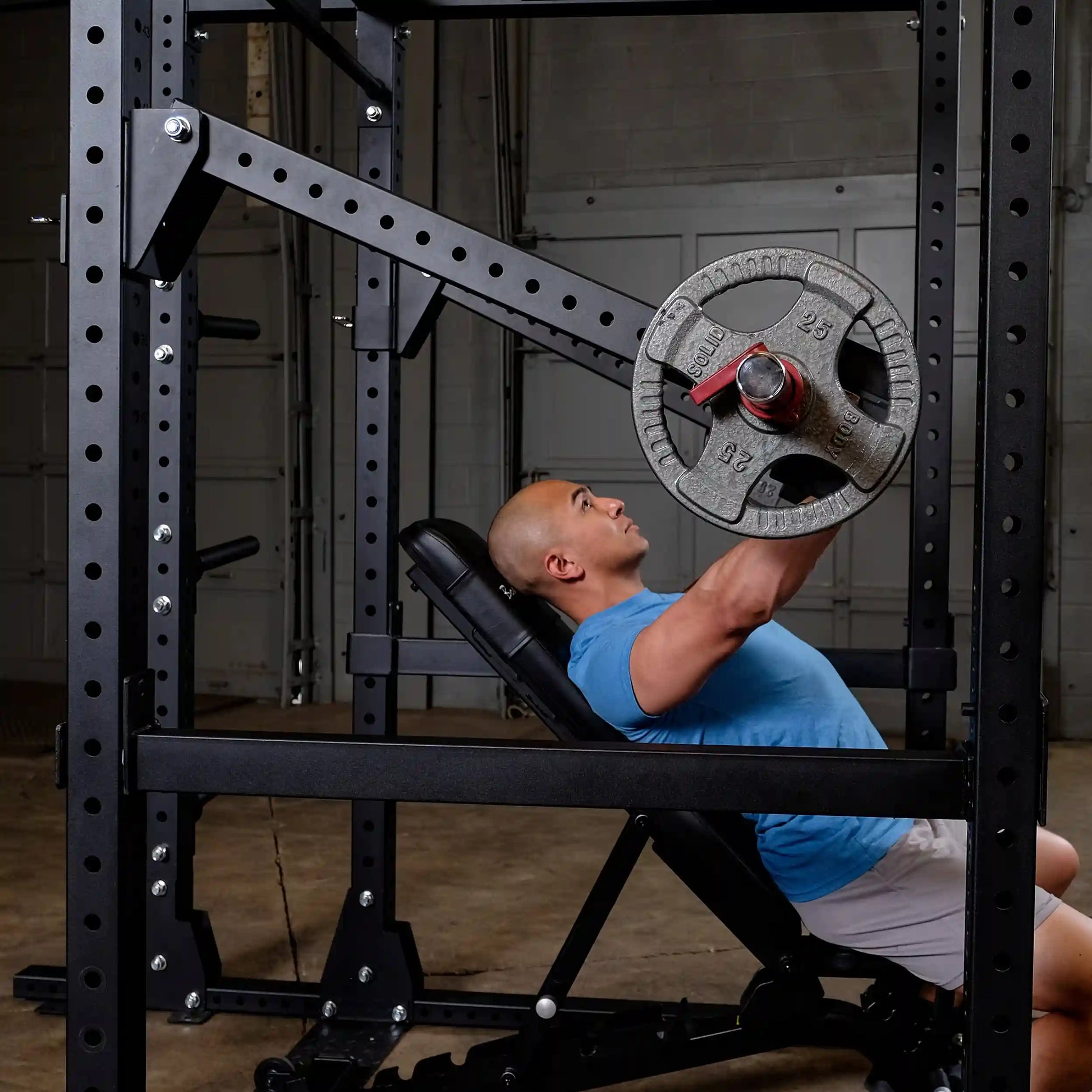 A person in a blue shirt using the Body-Solid Pro Clubline Jammer Arms SPRJAM for an incline press in a gym setting.