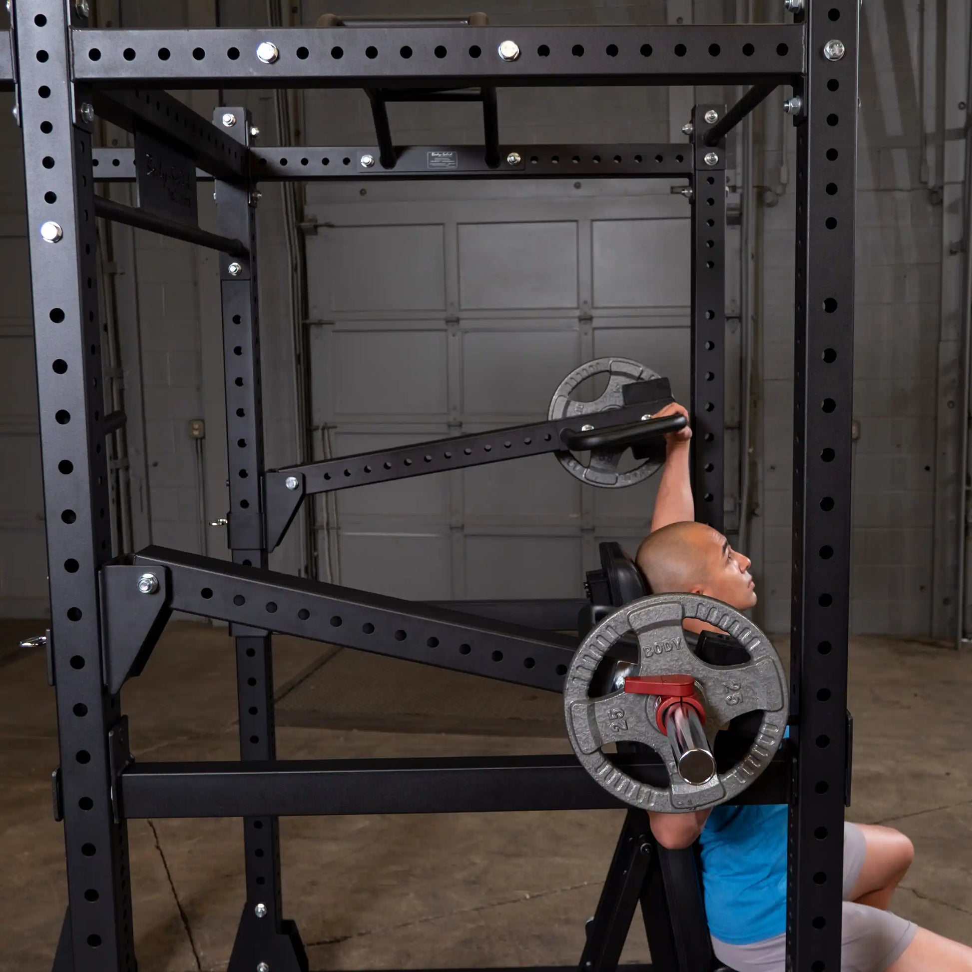 A person using the Body-Solid Pro Clubline Jammer Arms SPRJAM in a gym setting, demonstrating the arm exercise with weights attached.