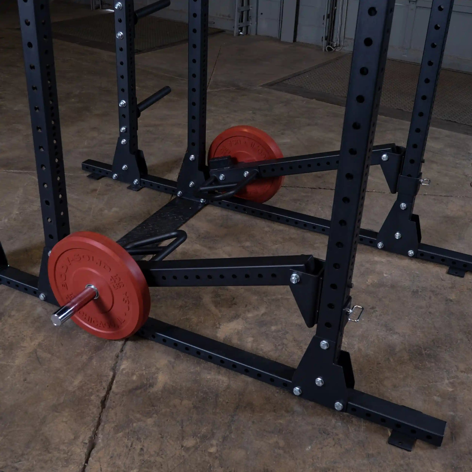 Body-Solid Pro Clubline Jammer Arms SPRJAM attached to a weightlifting frame with red weight plates on a gym floor.