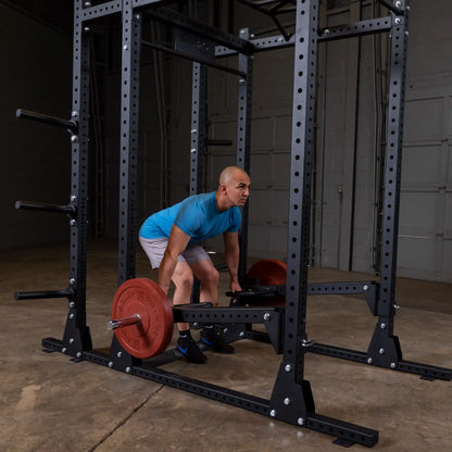 Person performing a deadlift using the Body-Solid Pro Clubline Jammer Arms SPRJAM in a gym setting, with a focus on strength training equipment and weights.