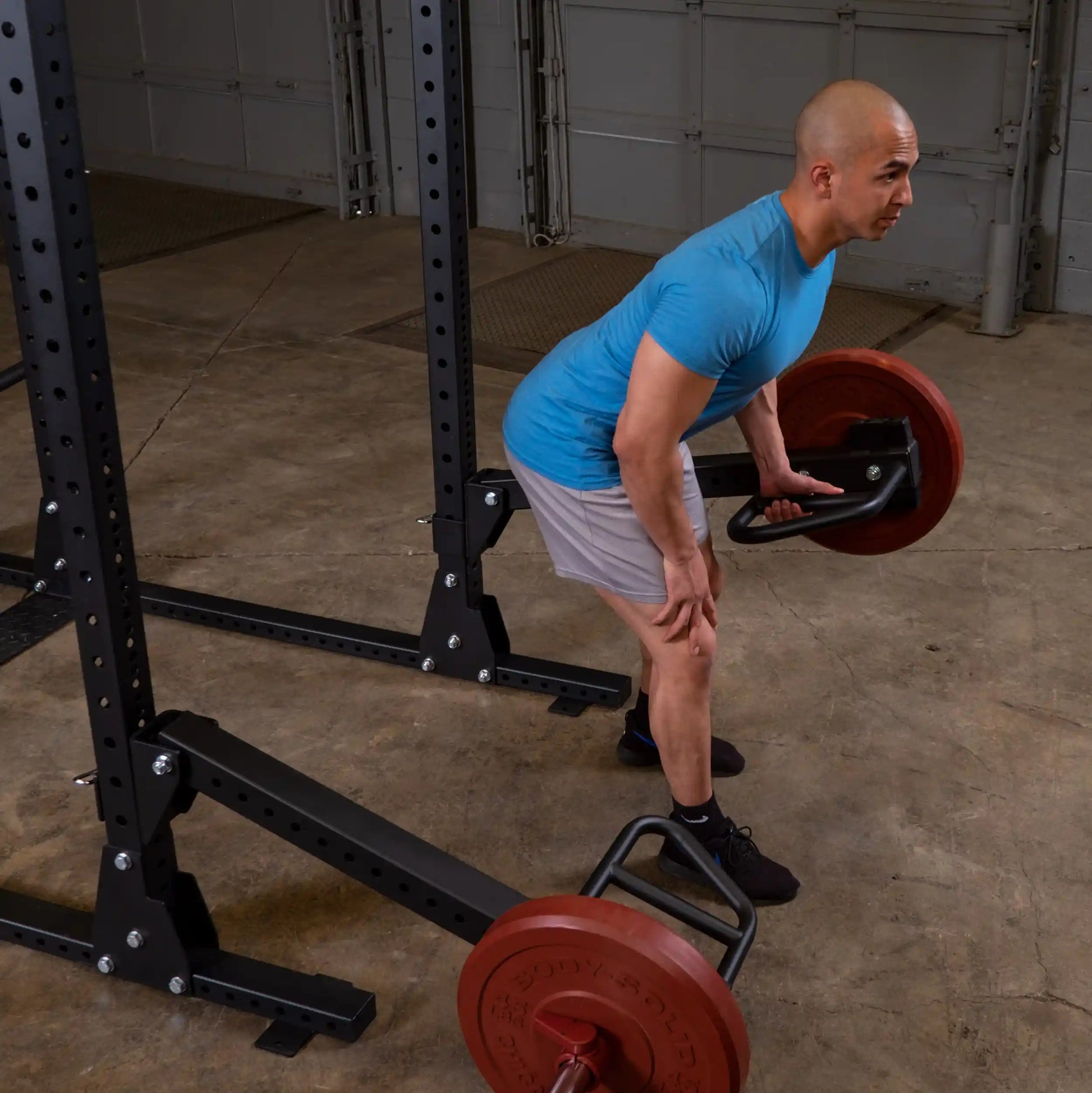 Man performing a deadlift using Body-Solid Pro Clubline Jammer Arms SPRJAM with weight plates in a gym setting.