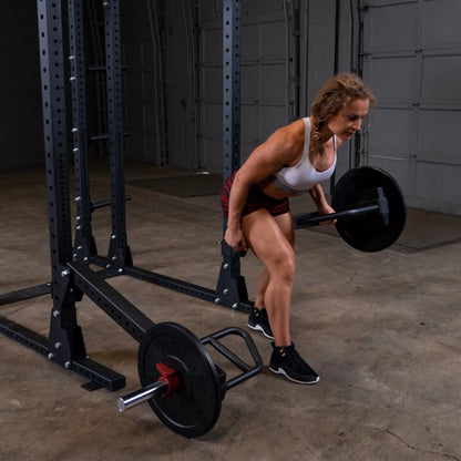 A person performing an exercise using the Body-Solid Pro Clubline Jammer Arms SPRJAM in a gym setting, focusing on strength training with a barbell.
