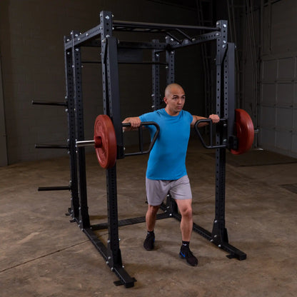 A person performing an exercise using the Body-Solid Pro Clubline Jammer Arms SPRJAM, with a barbell and weights inside a gym setting.