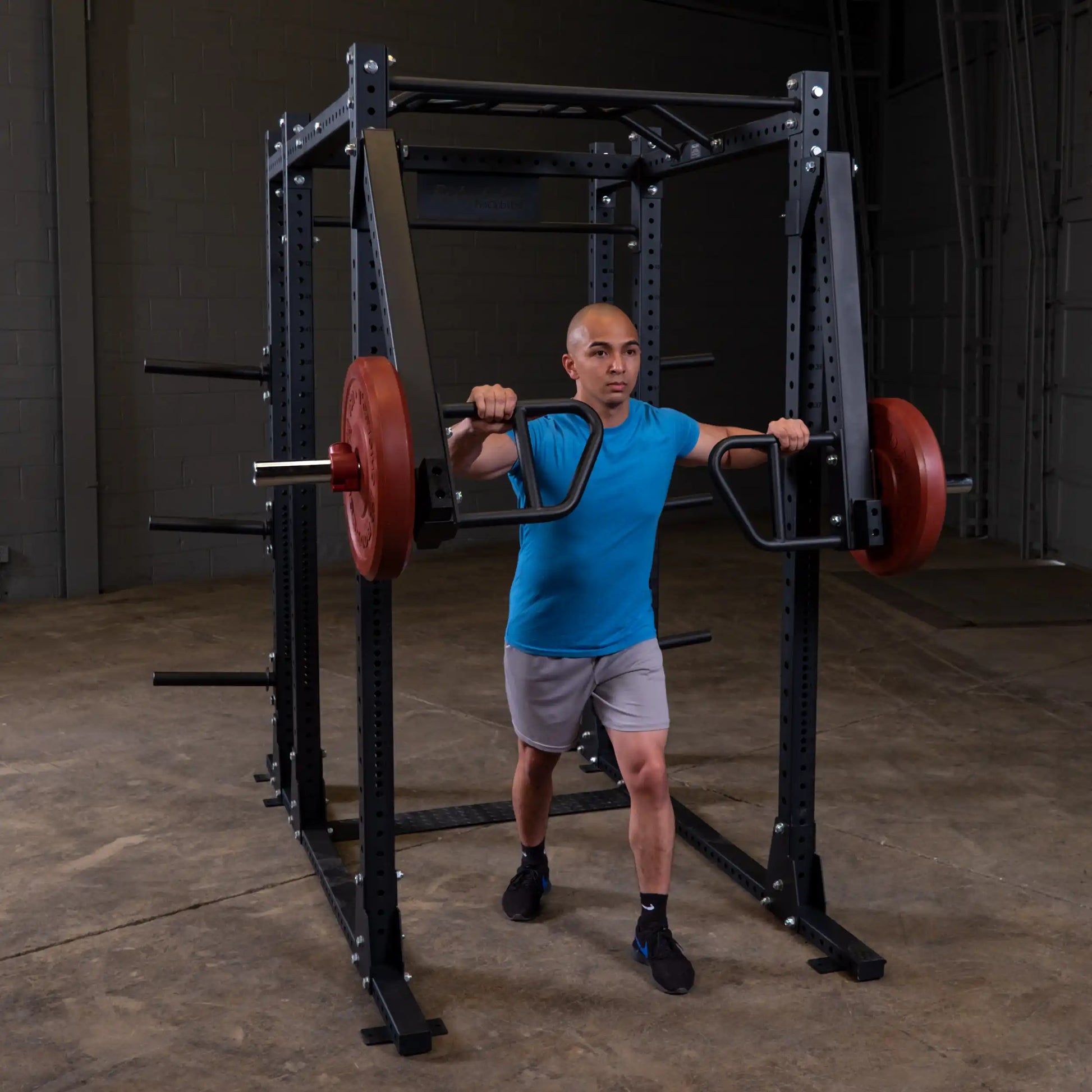 Individual using Body-Solid Pro Clubline Jammer Arms SPRJAM for a workout in a gym setting, showcasing strength training with weight plates attached.