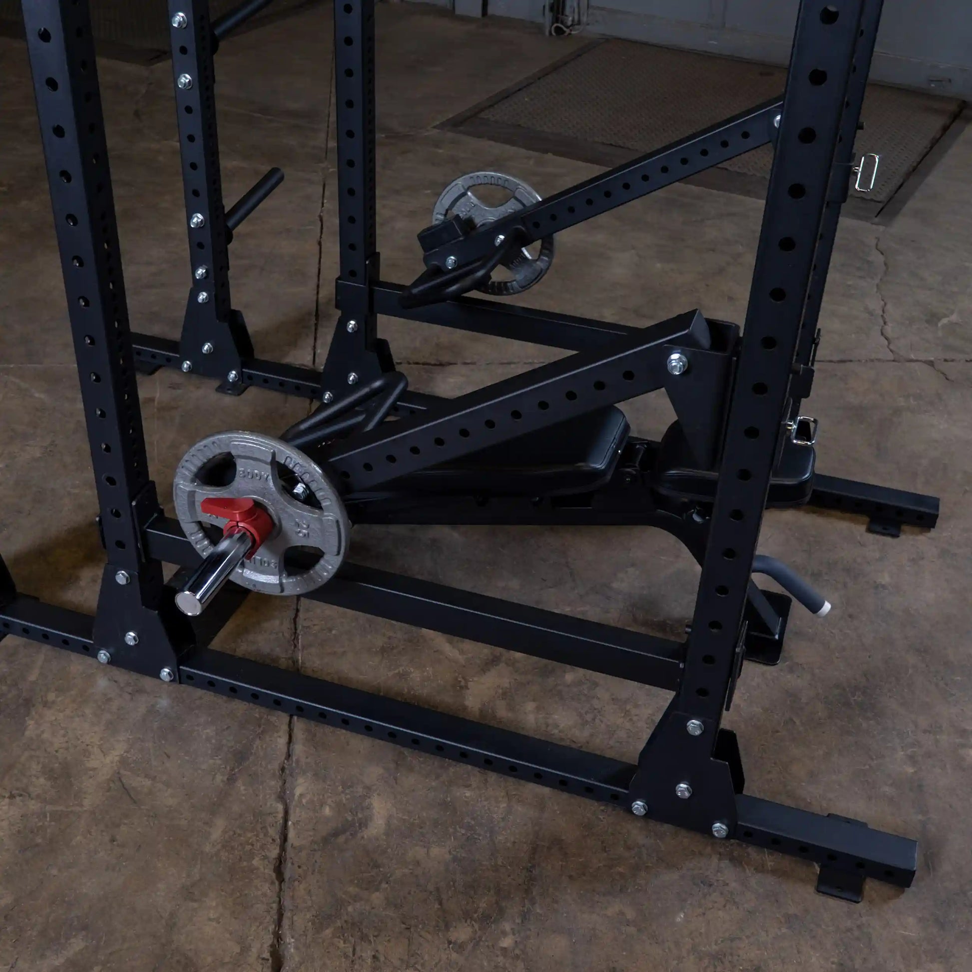 Close-up of the Body-Solid Pro Clubline Jammer Arms SPRJAM, showcasing its sturdy black steel construction with weight plates and adjustment mechanisms, on a concrete floor.