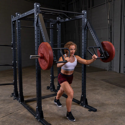 A woman using the Body-Solid Pro Clubline Jammer Arms SPRJAM to perform a strength exercise in a gym setting, showcasing an intense workout with weights on the machine.