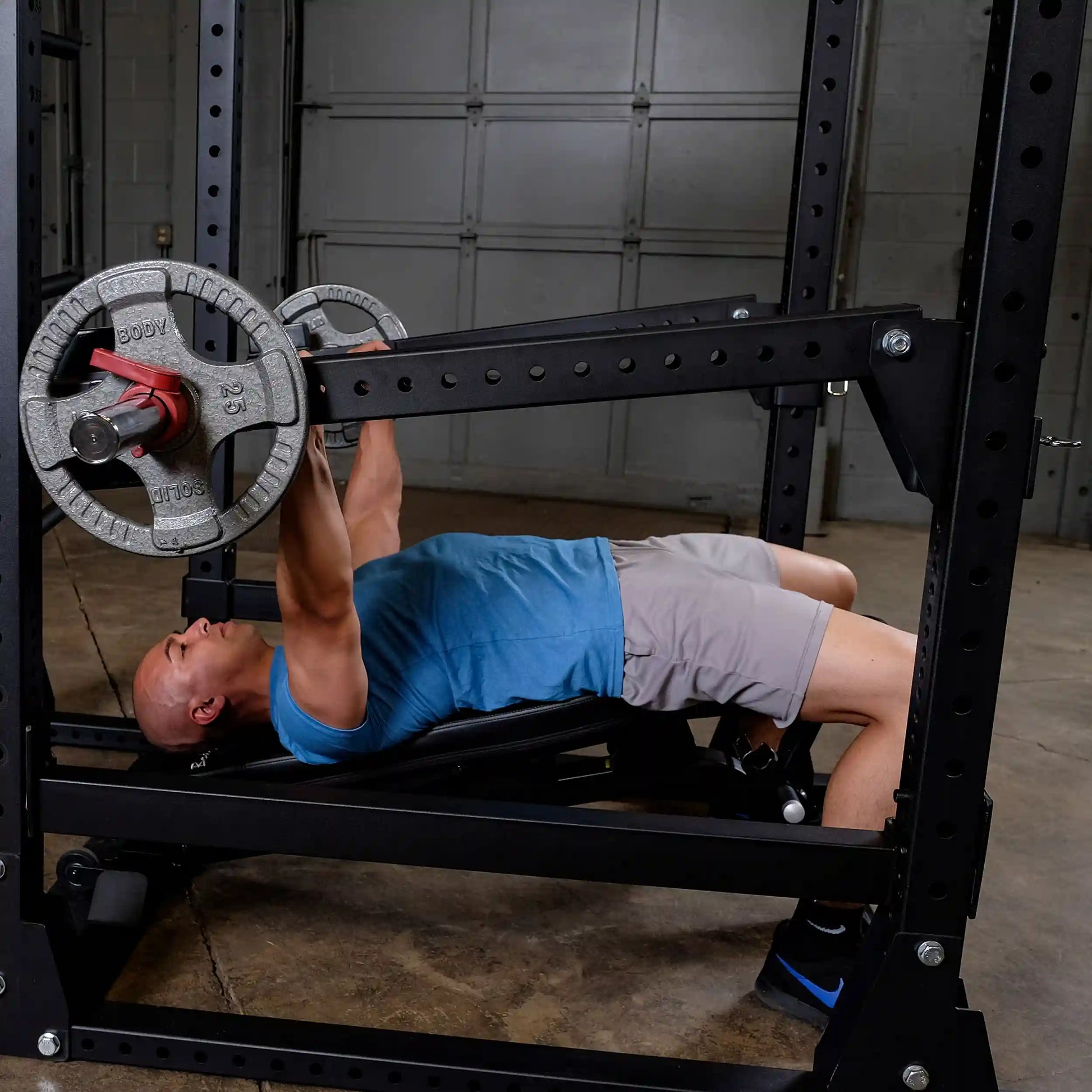 Man exercising on a bench press using Body-Solid Pro Clubline Jammer Arms SPRJAM in a gym setting.